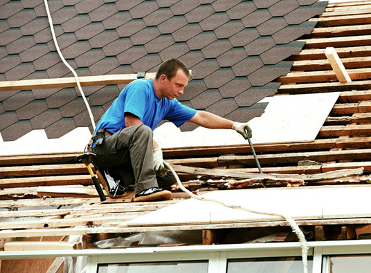 A man doing roofing services on a rooftop