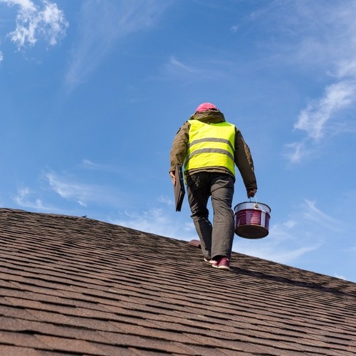 worker walking across a shingle roof