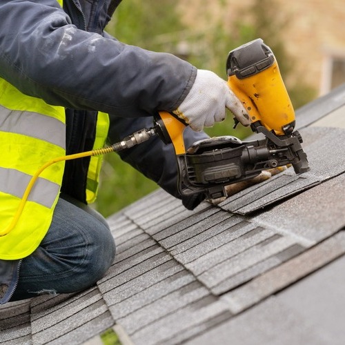 close-up of a worker nailing down shingles