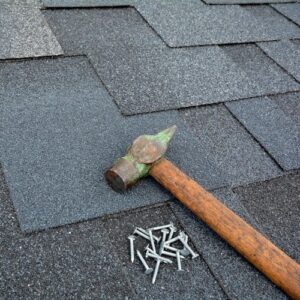 Rusty claw hammer with nails on asphalt shingles