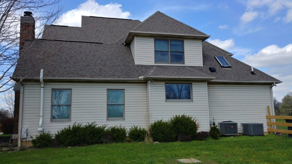 Two-storey home with light siding, a grey shingle roof and a skylight over the garage