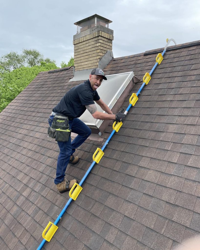 Kerrigan roofer carrying a ladder up to a roof for inspection