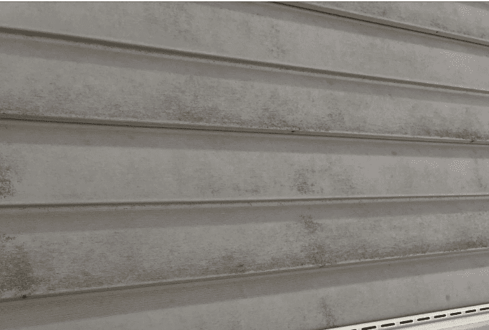 Close-up of a weathered vinyl siding panel during inspection
