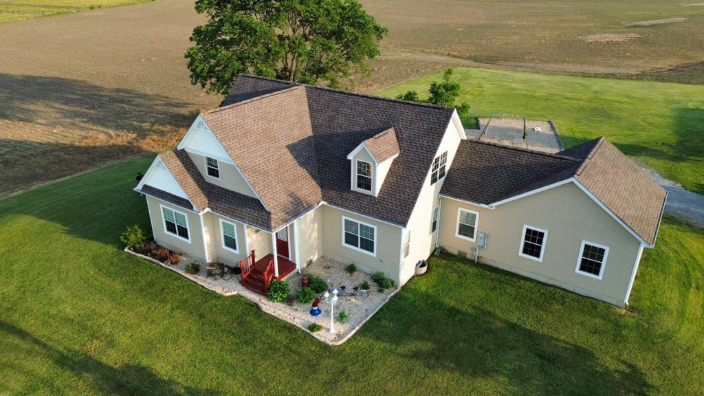 Aerial view of a cream ranch home with a new brown shingle roof