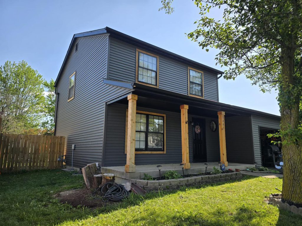 Two-storey grey home with timber porch posts and a new roof