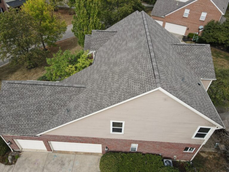 Aerial view of a beige home with a grey shingle roof