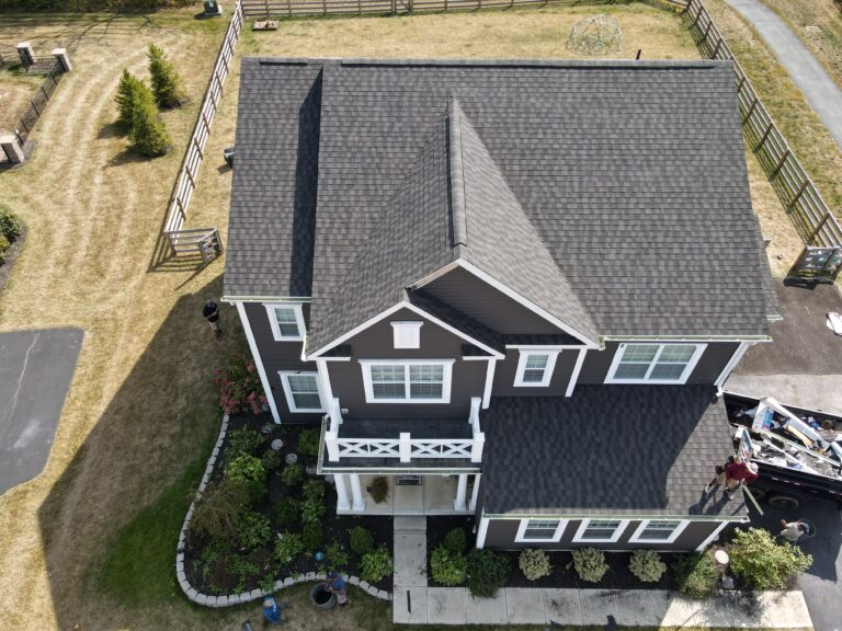Aerial view of a dark brown two-storey home with a grey shingle roof and white porch