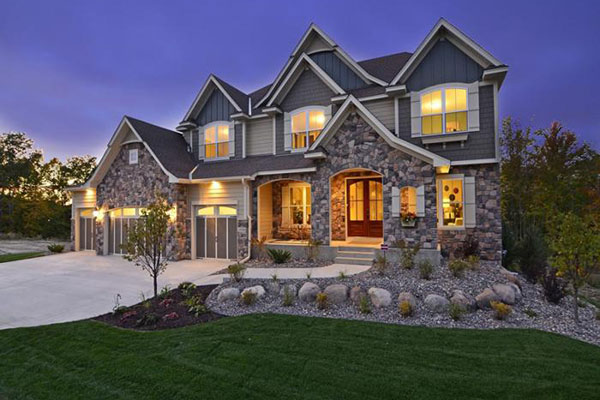 Large home with James Hardie siding and stone accents lit at dusk
