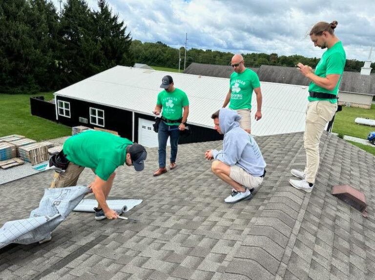 Kerrigan crew in branded shirts rolling out underlayment on a shingle roof