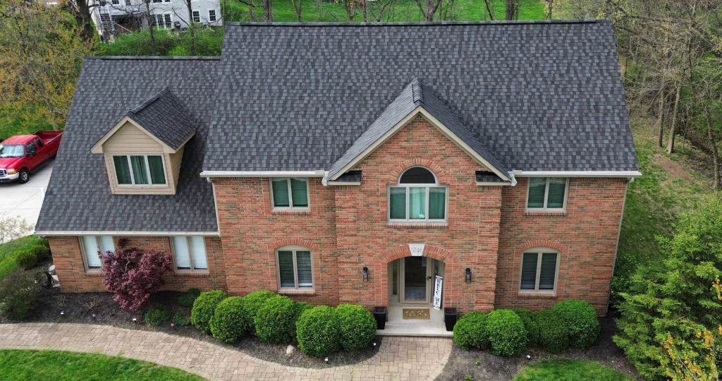 Brick colonial home with a grey shingle roof and multiple front windows