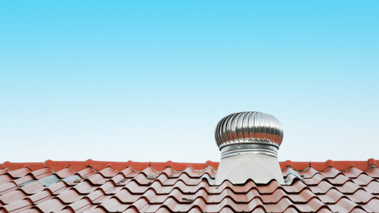 Silver turbine roof vent on a red tile roof against a clear sky