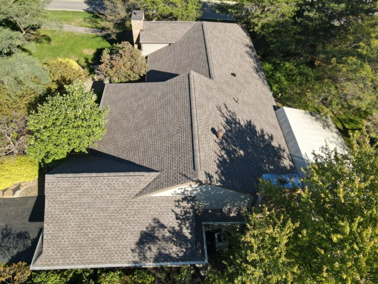 Aerial view of a wooded property with a newly shingled roof