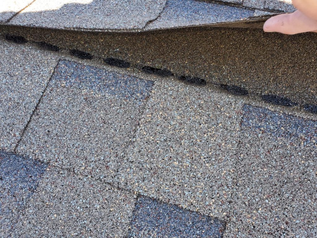 Roofer inspecting shingles during a repair assessment