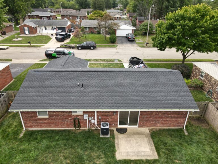 Aerial view of a brick ranch with a new dark grey shingle roof and a Kerrigan van on the street