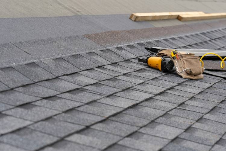 Close-up of grey architectural shingles with a roofer tool belt