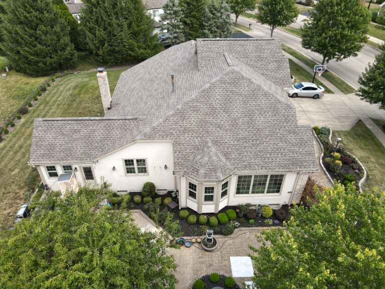Aerial view of a large landscaped home with a grey roof