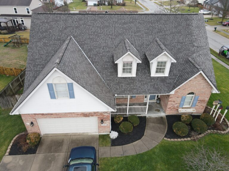 Brick home with dormer windows and a grey shingle roof