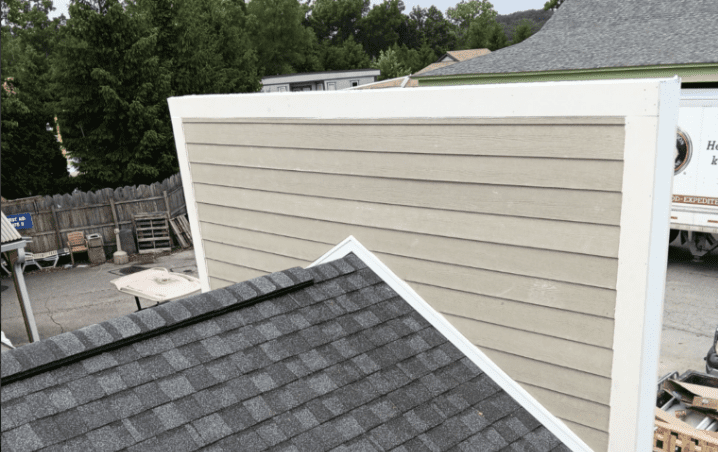 New grey shingles meeting cream lap siding at a roof-to-wall junction