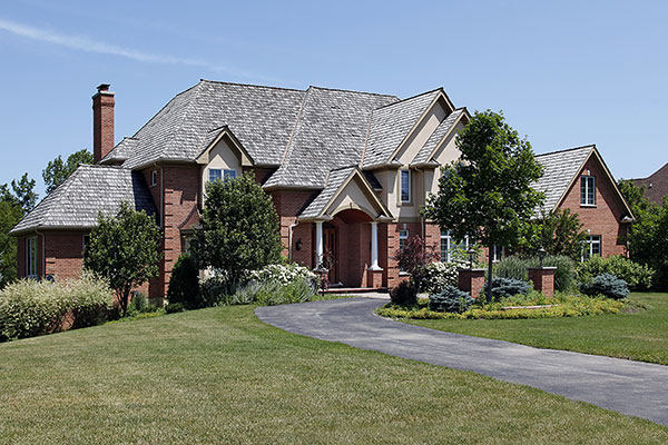 Brick two-storey home with a grey shake-style roof and landscaped driveway