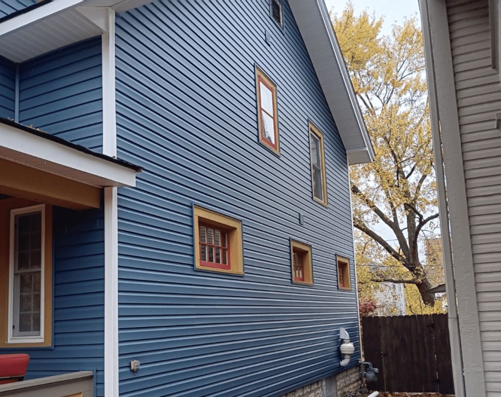 Deep blue vinyl siding with contrasting window trim on a two-storey home in autumn