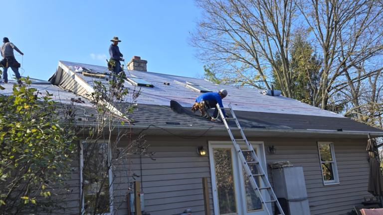 Roofing crew installing underlayment on a ranch home in late autumn