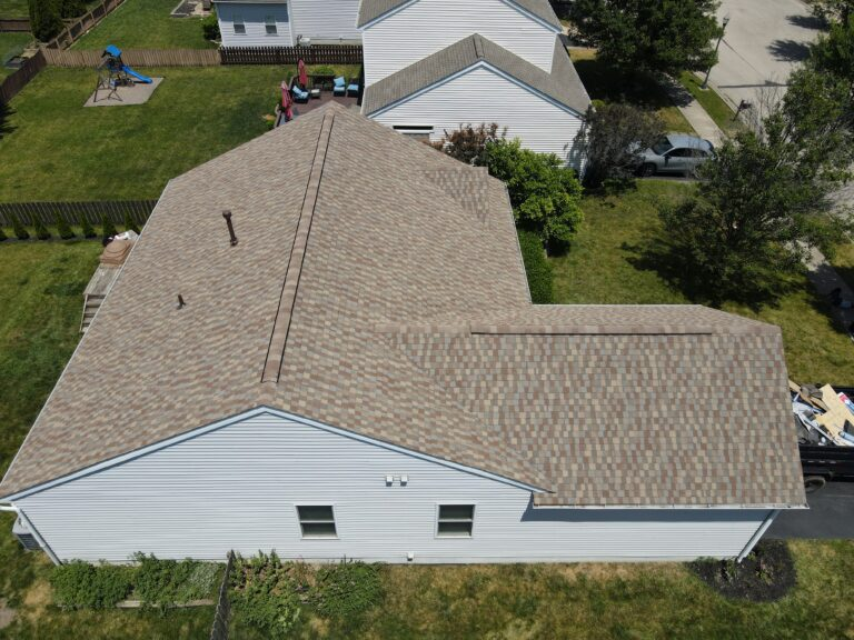 Aerial view of a white-sided home with new tan and brown blended shingles