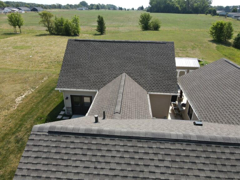Aerial view of grey shingle roofs on a rural home backing onto open farmland