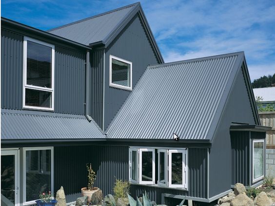 Dark grey corrugated metal roof and matching metal siding on a modern home