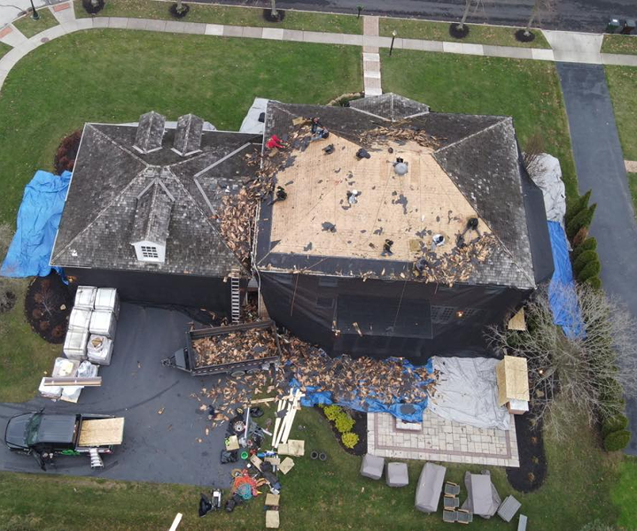 Roof before replacement, showing stripped decking and storm damage
