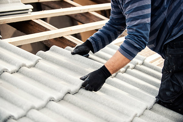 Roofer in gloves fitting a lightweight tile onto new roof battens