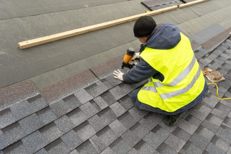 Roofer in a hi-vis vest fixing shingles on a roof slope